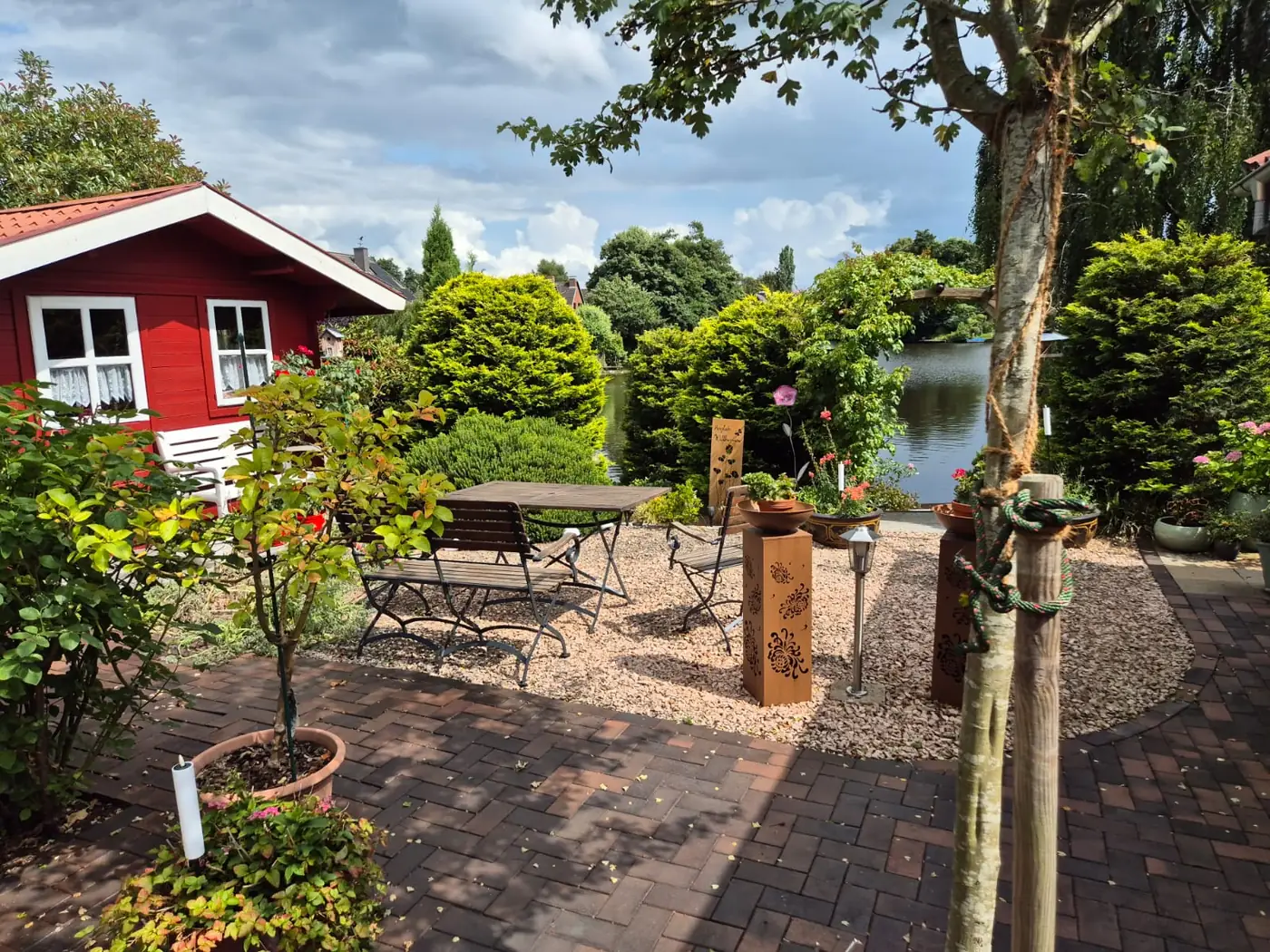 Sitzplatz mit Klinkerpflaster und Kiesbeet in einem Garten am Wasser