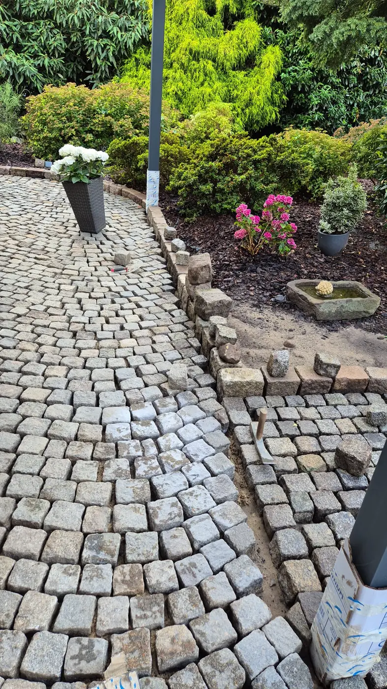 Geschwungener Gartenweg aus Natursteinpflaster mit Kanteneinfassung