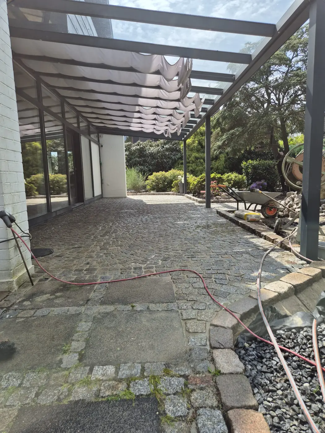 Terrasse mit Natursteinpflaster und Platten unter einer Terrassenüberdachung